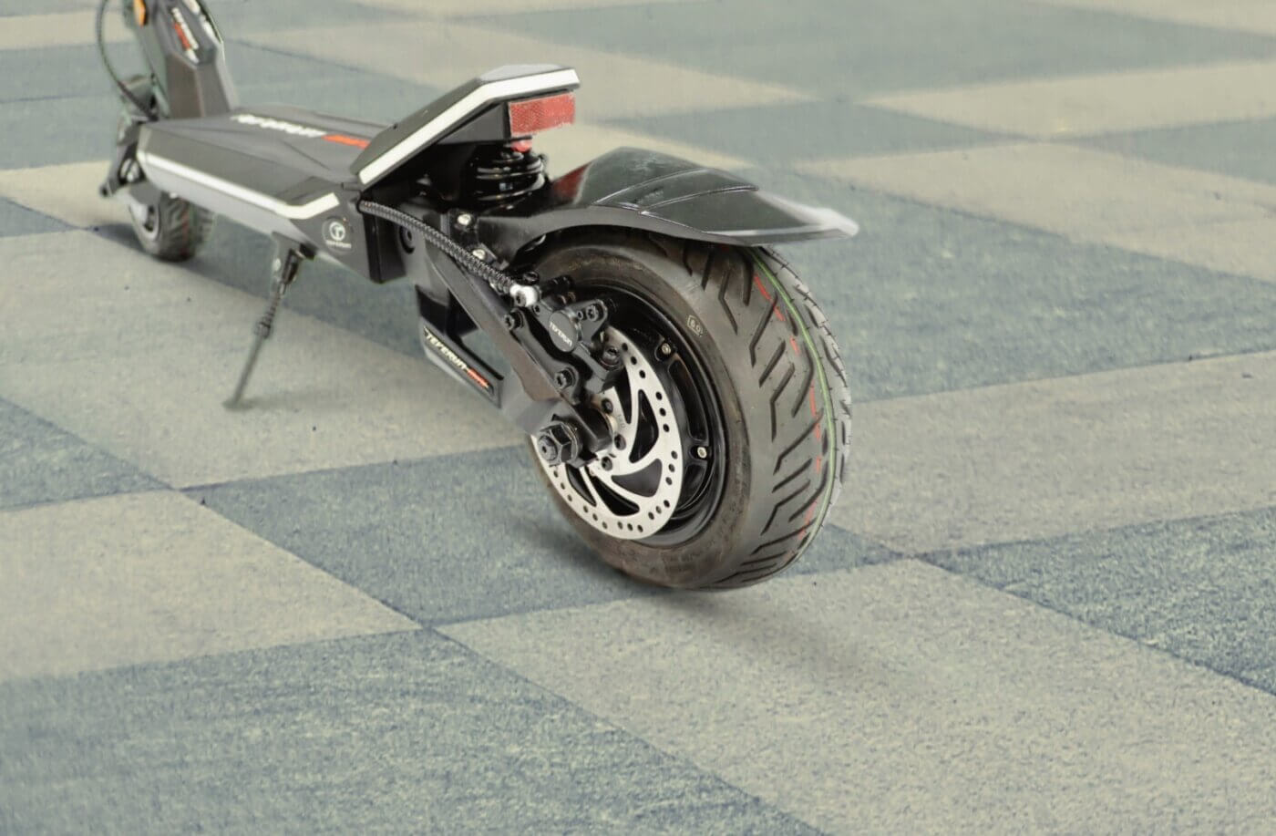The Fighter Mini electric scooter is parked on a checkered floor.