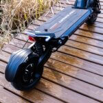 A black electric scooter, dubbed Fighter Supreme, resting on a wooden deck.