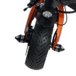 A close up view of the front tire of an orange motorcycle in motion.