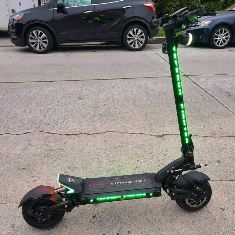 A scooter with green lights on the side of the road, resembling a Fighter 11.