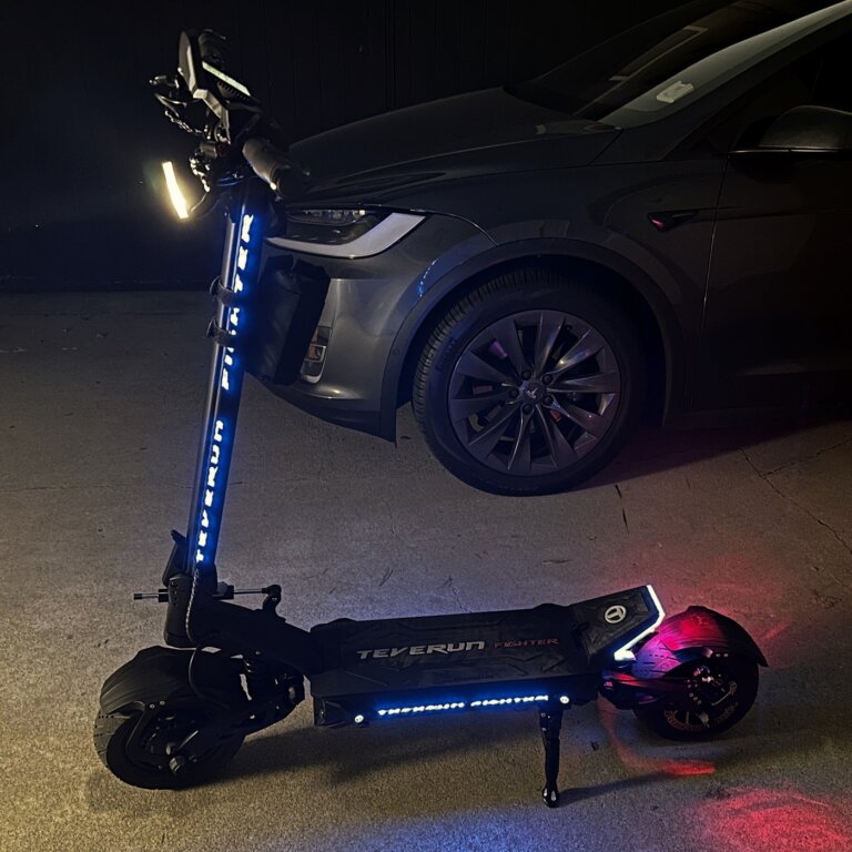 The electric scooter is parked in front of a car near the Fighter 11.