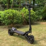 A black Fighter 11 electric scooter is parked in a grassy area.